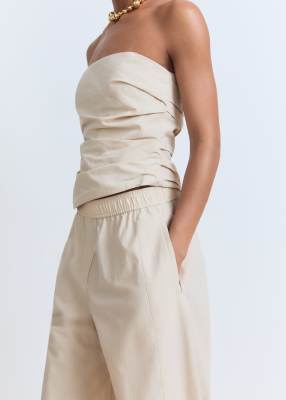 Conjunto blanco marfil de pantalones y top asimétrico con lateral fruncido y escote palabra de honor de Mango