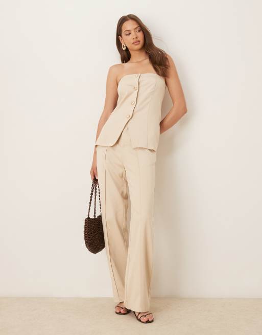 Conjunto color crema de pantalones de pernera ancha con pinzas delanteras y chaleco con escote palabra de honor y botones dorados de tejido efecto lino de SNDYS