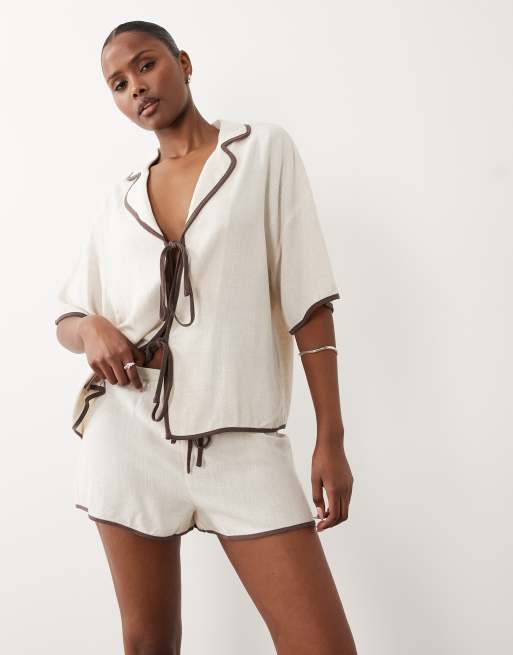 Conjunto playero color crema de pantalones cortos y camisa con solapas, lazada delantera y ribete en contraste de tejido efecto lino exclusivo de The Frolic