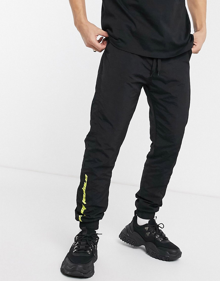 Criminal Damage - Nylon joggingbroek in zwart met neonkleurig logo
