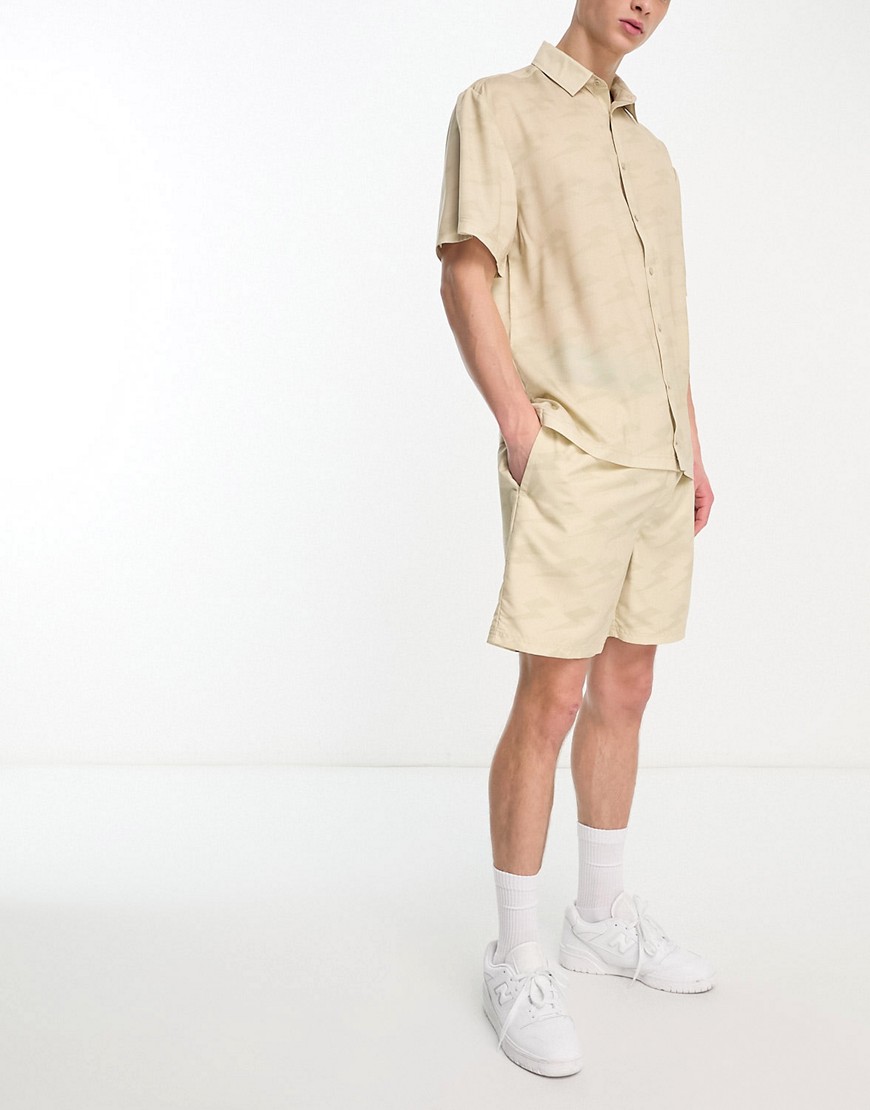 ellesse Capri co-ord shirt with lightning bolt print in beige-Brown