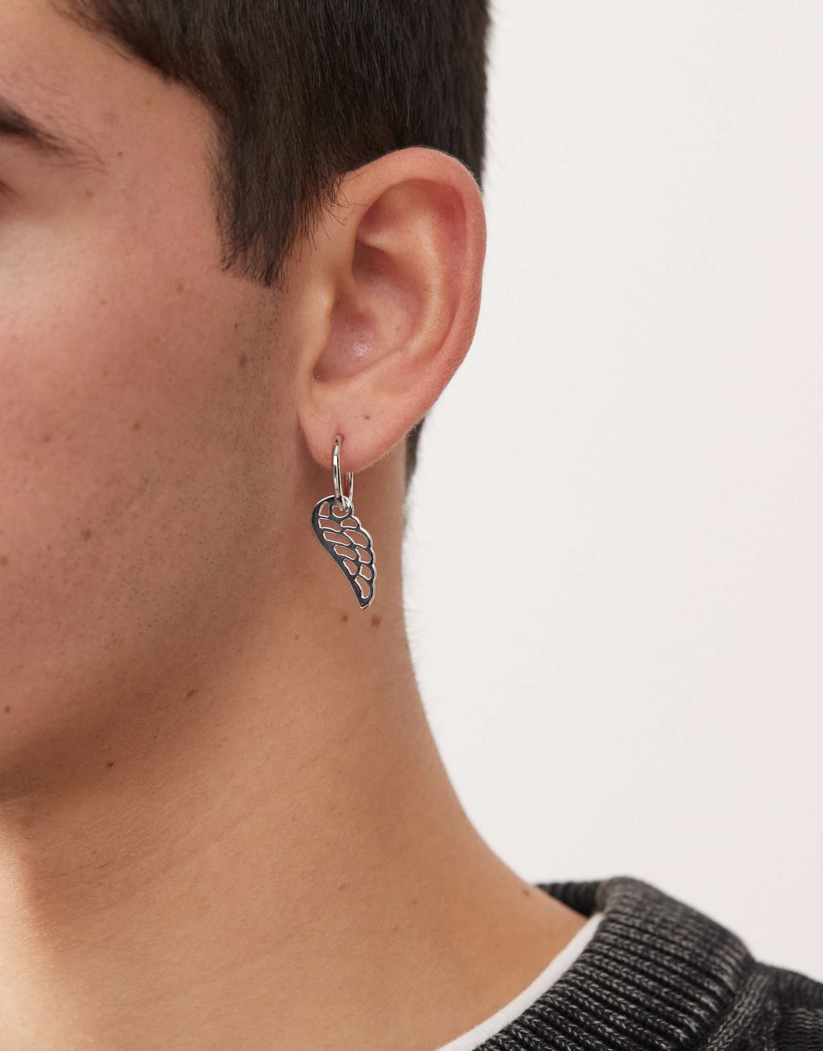 Выцветшая будущая серьга-обруч в виде крыла из одного пера серебристого оттенка