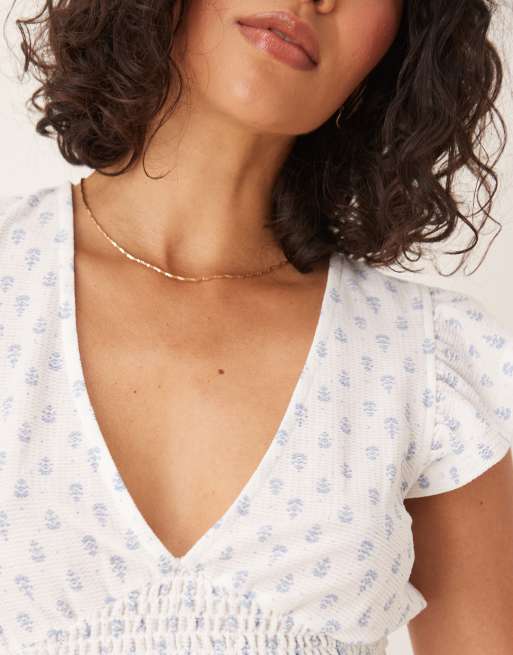 Gina Tricot - Top a maniche corte con stampa bianca e blu con scollo a V e volant, 3 di 4