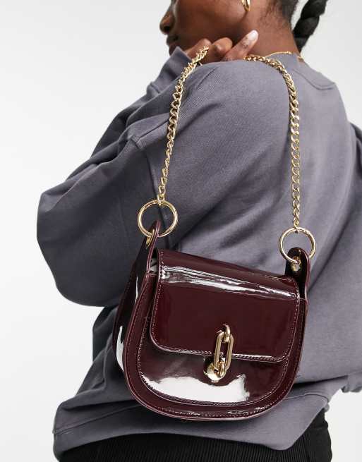 Glamorous patent saddle bag with gold hardware in oxblood