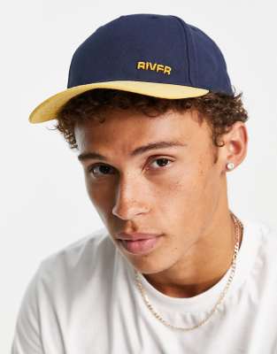 Gorra azul y mostaza con diseño color block de River Island