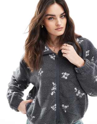 Hollister - Bestickte Fleece-Jacke in Schwarz mit Blumenmuster und Teddyfellfutter