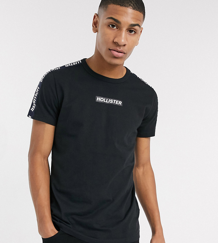 Hollister - T-shirt in zwart met logo op de borst en mouwtape - Exclusief op ASOS