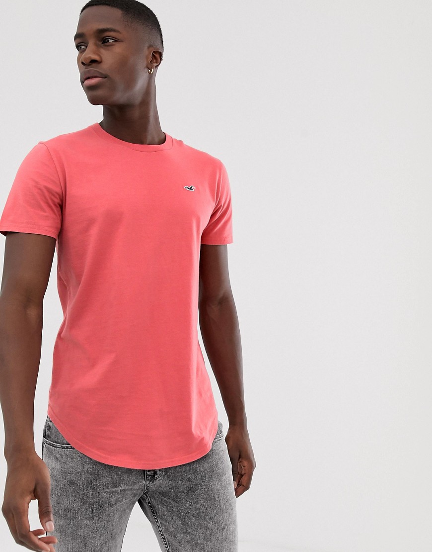 Hollister - T-shirt rosa salmone con fondo arrotondato e logo