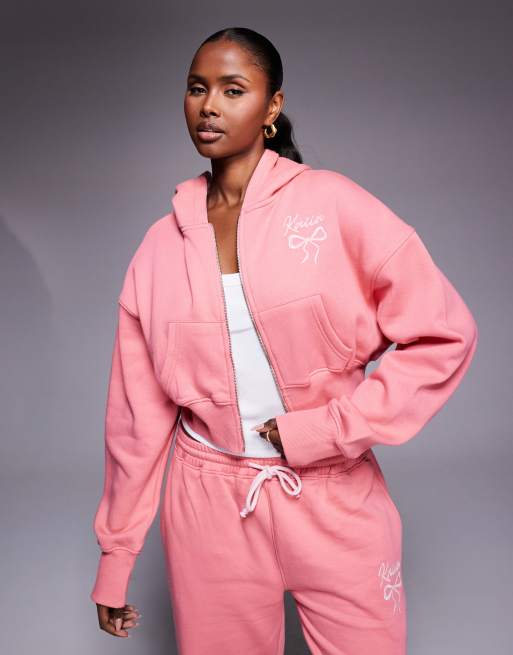 Kaiia – Set in Koralle und Babyrosa, bestehend aus kurzärmligem Cropped-Oberteil mit Rundhalsausschnitt und Schleifen-Logo, Kapuzenpullover und Jogginghose, 4 von 4