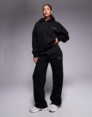 Kaiia - Exclusive - Jogginghose mit hohem Baumwollanteil in Schwarz, weitem Bein und strassbesetztem Logo, Kombiteil