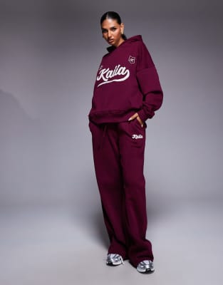 Kaiia - Jogginghose mit hohem Baumwollanteil in Burgunderrot und Creme mit Schriftzuglogo im Schaumprint und weitem Bein...