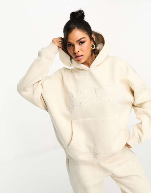 Studio portrait of woman in sports bra and hooded shirt Stock