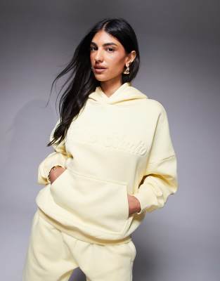 Kaiia Studio - Oversize-Kapuzenpullover in Gelb mit geprägtem Logo, Kombiteil