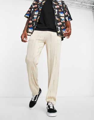 Liquor N Poker straight leg plisse trousers in beige with all over japanese text print