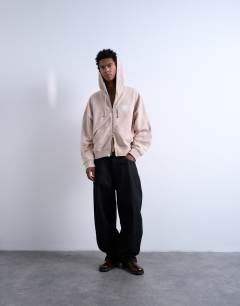 Model wearing Mason Newman x Topman boxy fit hoodie with hotel bar front and back print in washed stone
