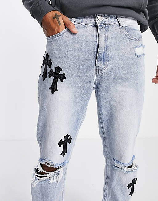 Mennace loose fit denim jeans in mid wash with rips and cross print
