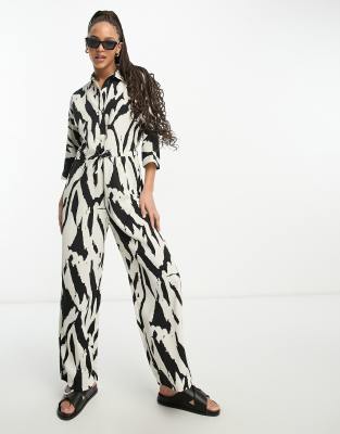 Monki - Jumpsuit mit Taillenbindung mit Druck in Schwarz und Beige-Bunt