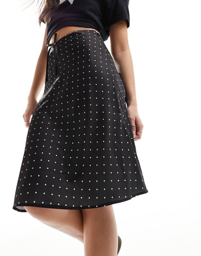 Monki - satin a-line midi skirt with front bow detail in black and white polka dot