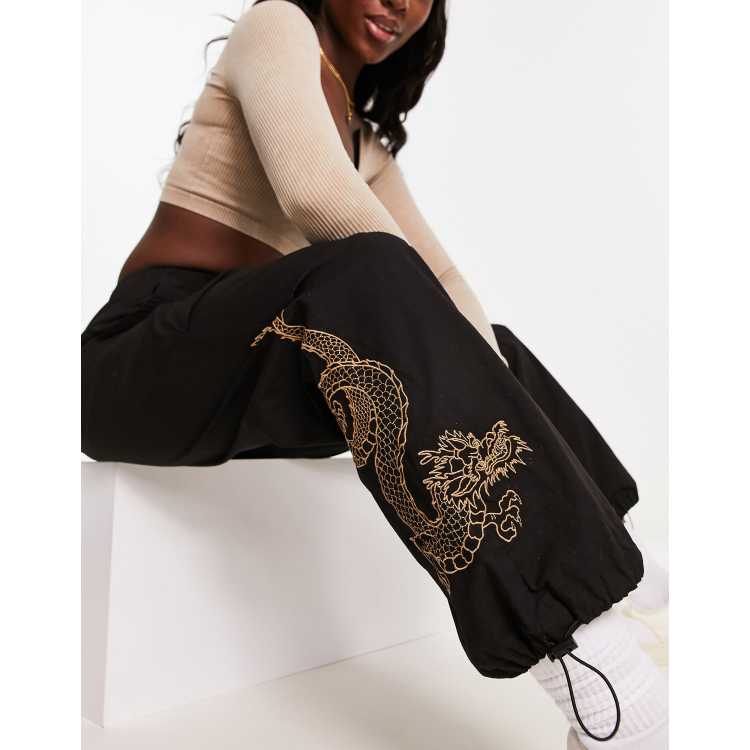 New Look embroidered dragon parachute trousers in black