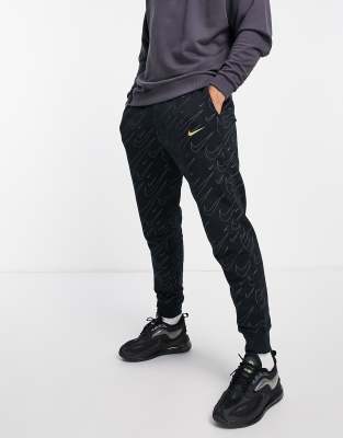 Nike all over swoosh print cuffed joggers in black and gold