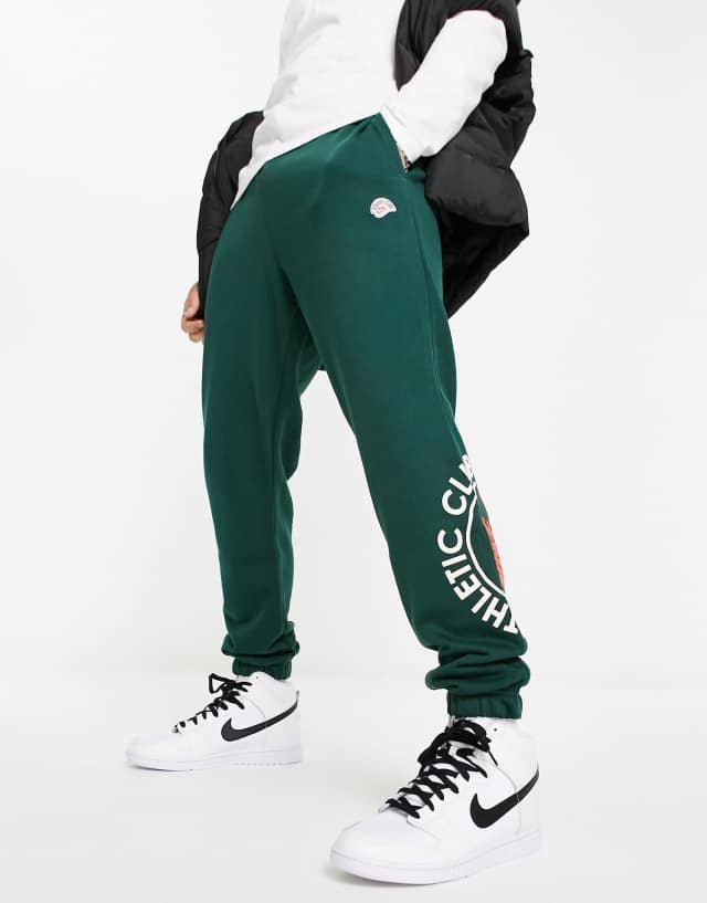 Nike Athletic Club retro logo casual fit cuffed joggers in dark green