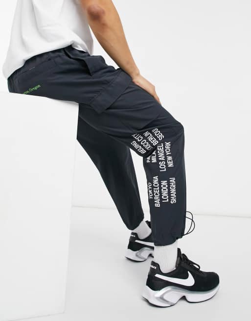 Nike World Tour Pack Graphic Woven Cuffed Cargo Trackies In Black Asos