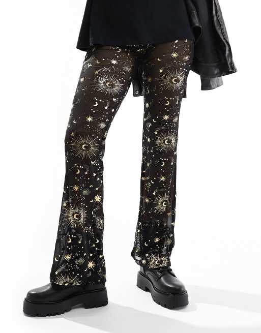 Noisy May - Pantaloni con fondo ampio in rete nera con laminatura color oro a tema cosmico