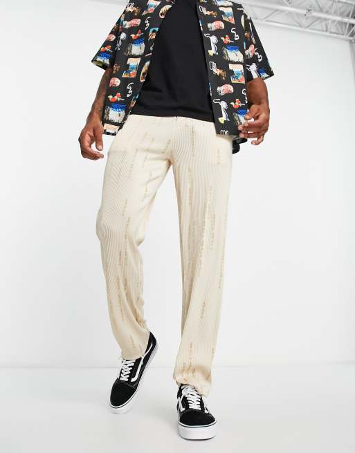 Pantalones beis plisados de pernera recta con estampado integral de texto en japonés de Liquor N Poker