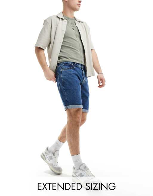 Pantalones cortos vaqueros azules elásticos de corte slim y largo estándar con lavado medio de ASOS DESIGN