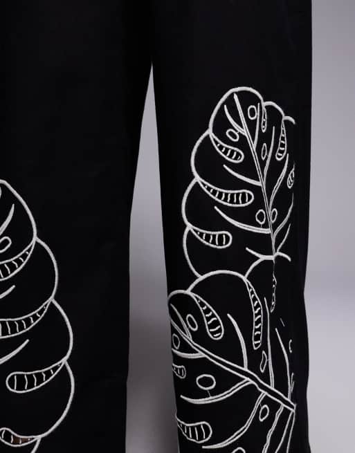 Pantalones negros con diseño tropical calado Jasmine Beach de ASOS DESIGN, 2 de 5