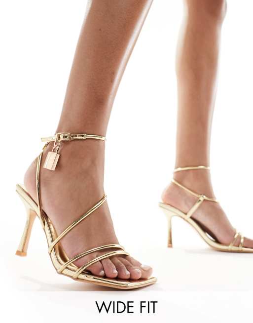 Public Desire Wide Fit – Emberly – Sandaletten in Gold mit Vorhängeschlossdetail und mittelhohem Absatz, weite Passform