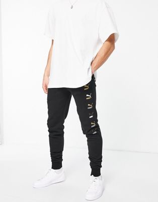 Puma all over logo print joggers in black and gold