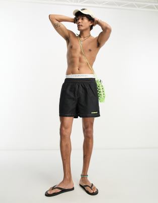 Reclaimed Vintage contrast stitch swim shorts in black