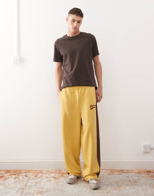 Reclaimed Vintage – Jogginghose in Senfgelb mit weitem Bein und braunen Seitenstreifen