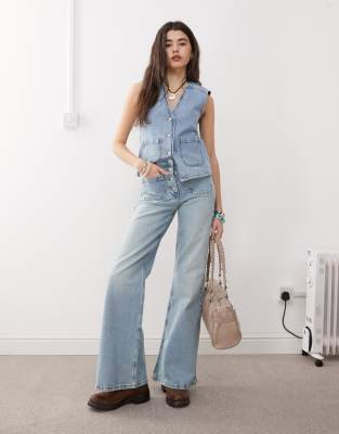 Reclaimed Vintage - Palazzo-Jeans im Stil der 70er mit aufgesetzten Taschen und Knopfverschluss in blauer Waschung