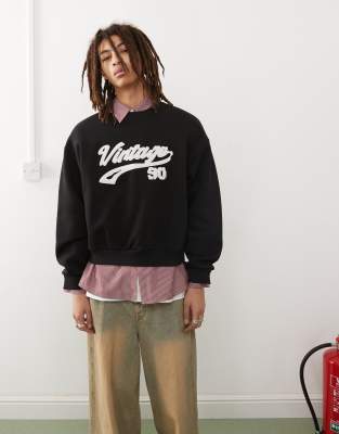 Reclaimed Vintage – Svart, tvättad sweatshirt i oversize och kort design med boxig passform och applicerad collegelogga