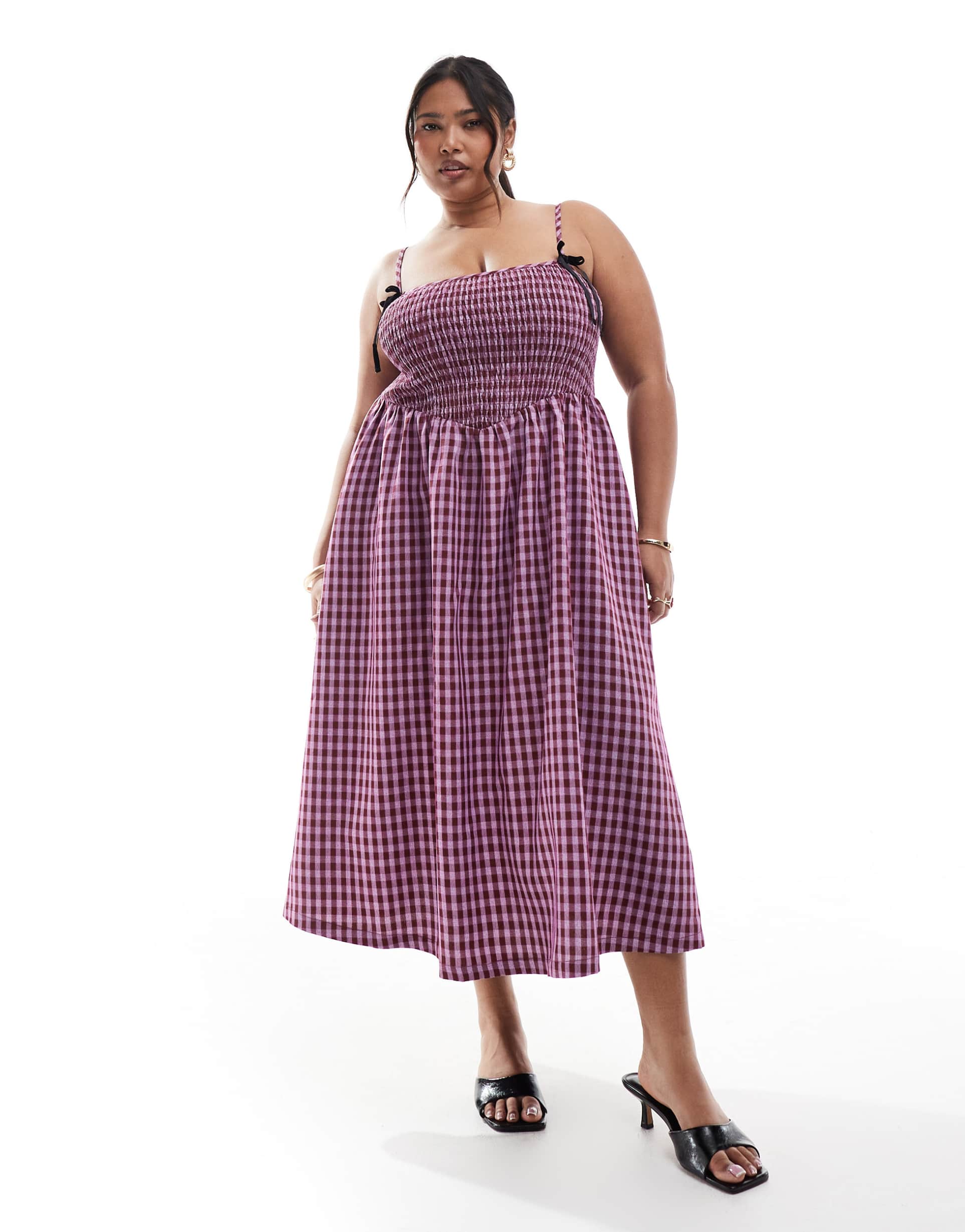 A plus-size pink and black ginghm midaxi dress with bows on the straps