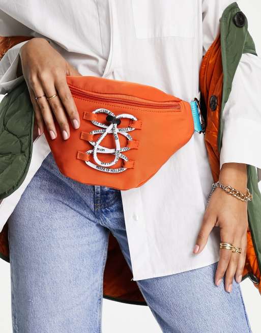 Riñonera naranja estilo bandolera con logo en la correa y detalle de cordón de House of Holland