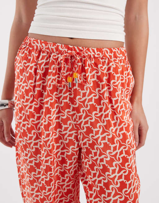 River Island monogrammed print trousers in orange , 3 of 5