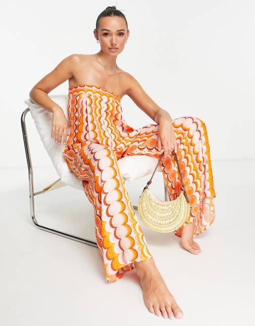 River Island – Pomarańczowy kombinezon plażowy z dekoltem bandeau we wzór w stylu lat 70. z wiązaniem na plecach