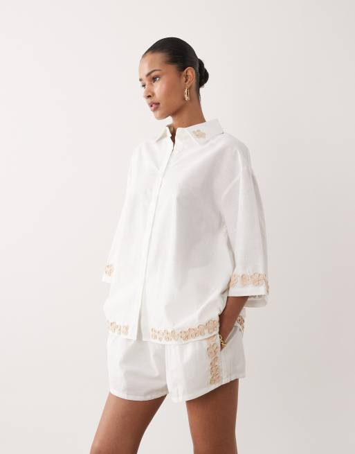 SNDYS - Coordinato in misto lino e cotone bianco con pantaloncini a vita alta e camicia oversize con applicazioni floreali, 2 di 3