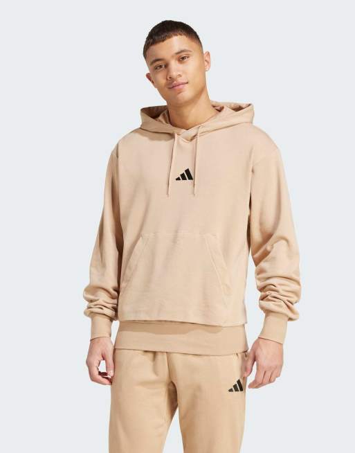 Sudadera color arena cálido y negra con capucha de felpa rizada Essentials Feelcozy de adidas Performance