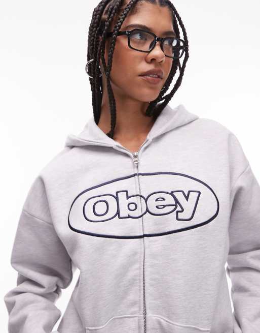 Sudadera gris claro con capucha, cremallera y logo ovalado de tejido muy grueso de Obey, 2 de 4