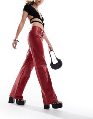 The Kript Y2K low rise trousers in red faux leather with silver belt detail