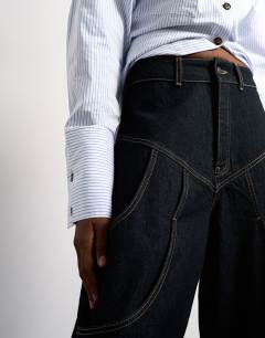 Model wearing Tolu Coker x Topshop barrel high rise jean circular design in indigo rinse