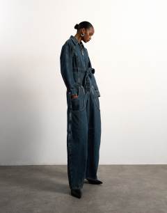 Model wearing Tolu Coker x Topshop denim barrel leg jumpsuit circular design in deep blue
