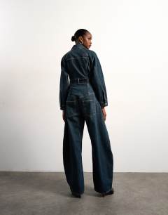 Model wearing Tolu Coker x Topshop denim barrel leg jumpsuit circular design in deep blue