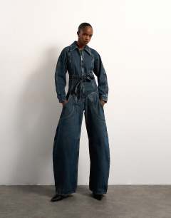 Model wearing Tolu Coker x Topshop denim barrel leg jumpsuit circular design in deep blue
