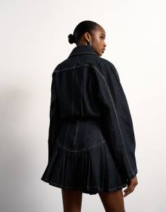 Model wearing Tolu Coker x Topshop denim super mini pleated skirt circular design in deep blue