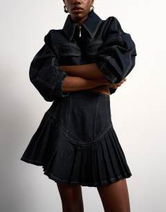 Model wearing Tolu Coker x Topshop denim super mini pleated skirt circular design in deep blue